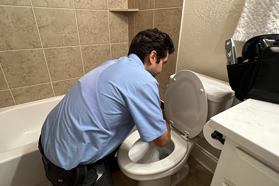 CW Service Pros plumber performing toilet plumbing repair