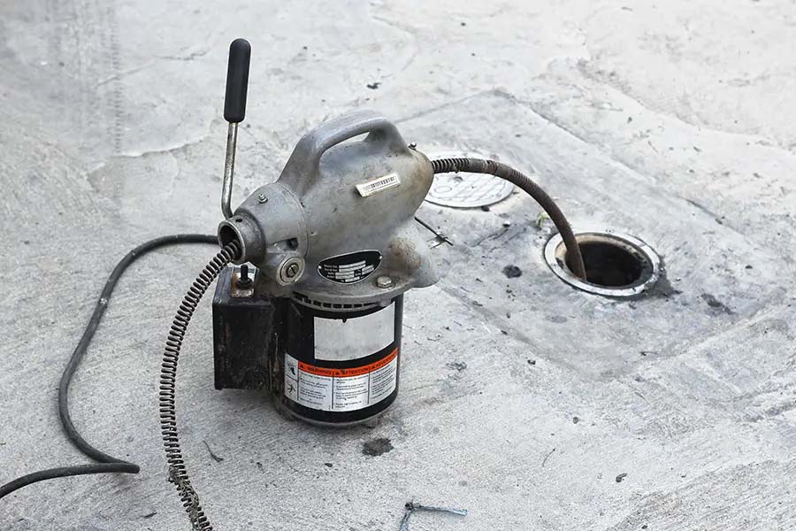 Sump pump drain line cleared with power auger