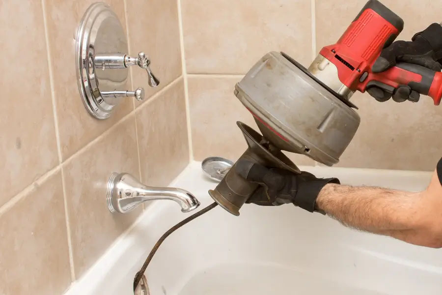 Drain cleaning technician unclogging bathtub drain in Lewisville, TX