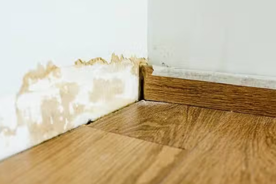 Slab leak causing water damage along wall and flooring