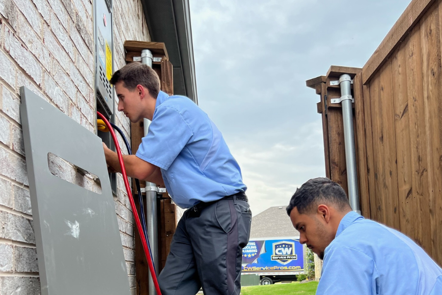 Plumbers from CW Service Pros are diagnosisng an issue on a tankless water heater and flushing the system