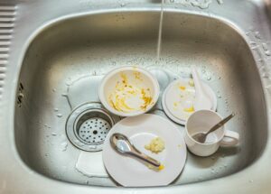 dirty plates and silverware in stainless steel sink