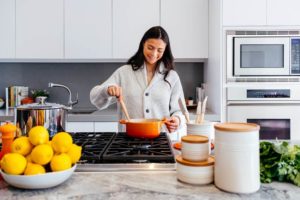 woman stirs orange pot in kitchen